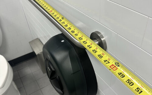 Grab bar length being measured in an accessible restroom